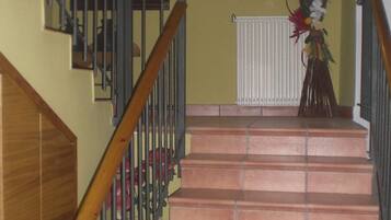 Una escalera con barandillas de madera y pasamanos metálico que sube a un piso superior.