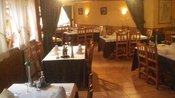 Een restaurant met meerdere tafels gedekt voor diners, met een klassiek interieur en houten stoelen en tafels.