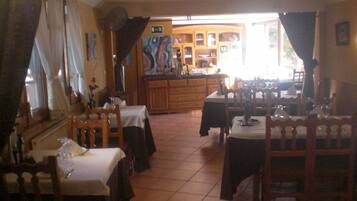 Un ristorante con diversi tavoli e sedie, una zona cucina sullo sfondo e vista sulla strada.