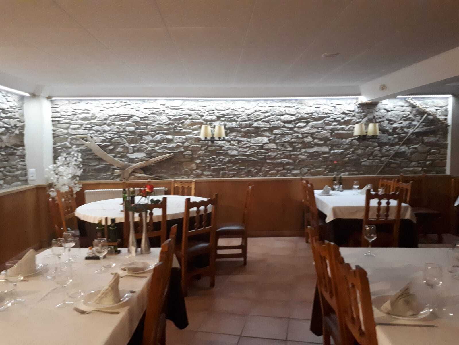 A restaurant with stone walls, round tables, and wooden chairs.