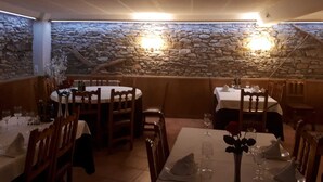 A restaurant with stone walls, wooden tables, and chairs. - Hotel Roch (Sort)