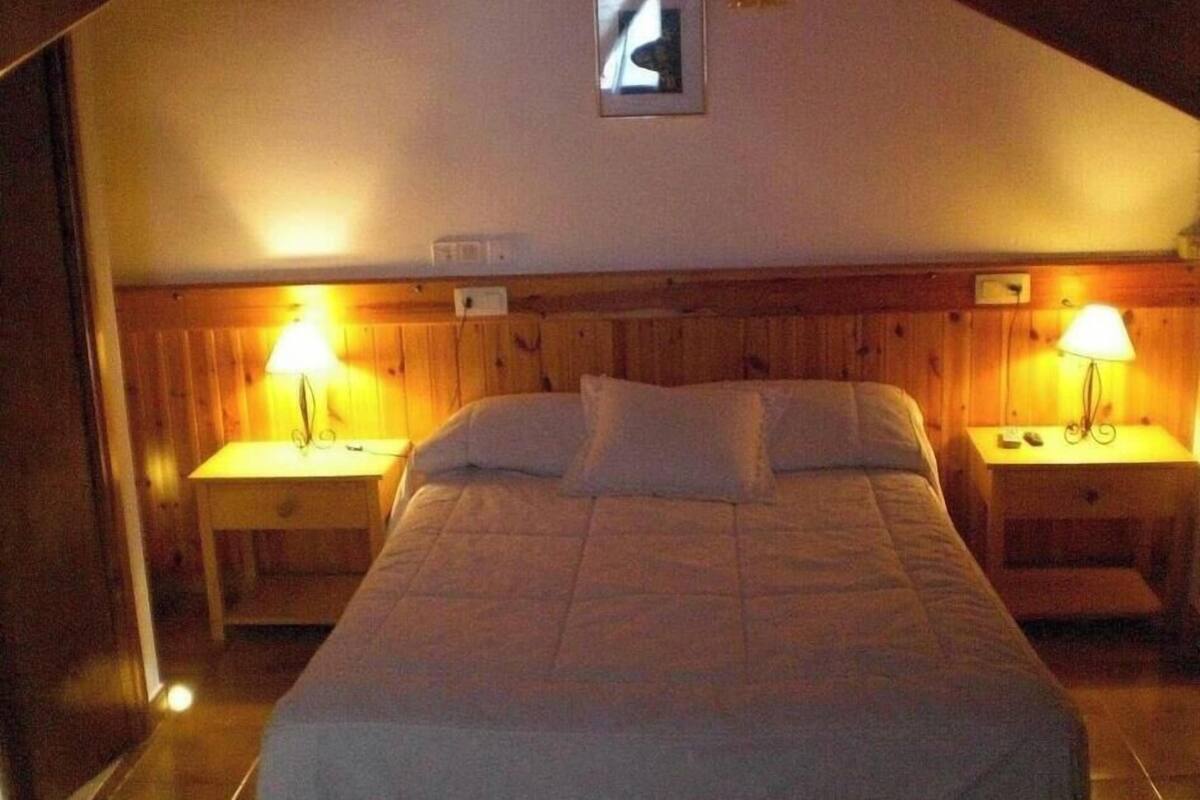 A bedroom with a single bed, two bedside tables, and two wall-mounted lamps.