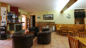 A cozy living room with a fireplace, leather sofas, wooden furniture, and a television. - Hotel Roch (Sort)