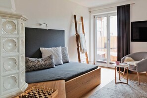 Ein Schlafzimmer mit Bett, Kommode, Stuhl, Fernseher und Balkon.