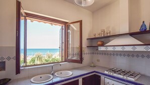Un baño con un ventanal grande, un lavamanos, un espejo y una estufa a gas.