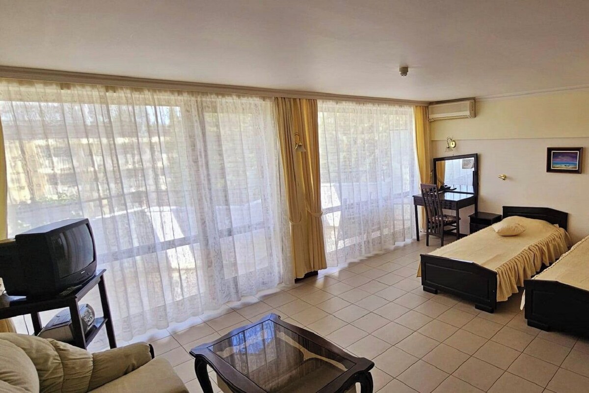 A hotel room with two beds, a TV, a desk, and a chair.