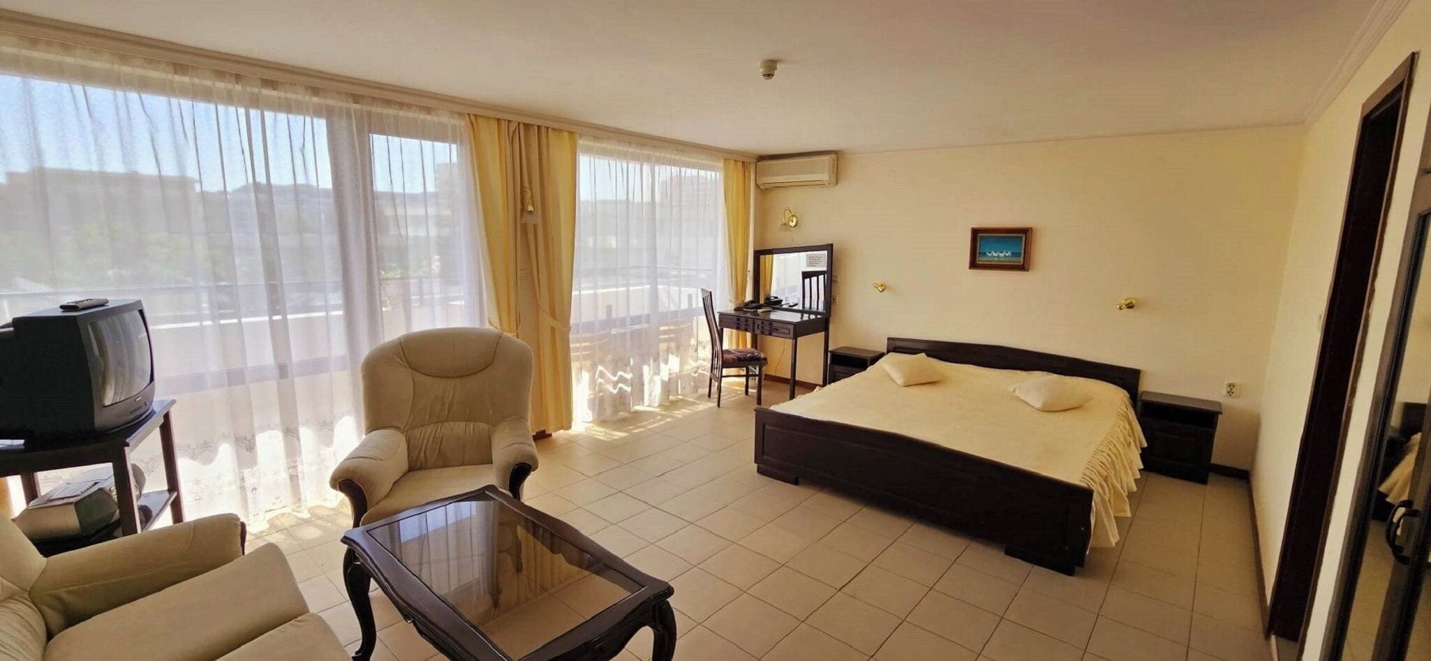 Une chambre d’hôtel équipée d’un lit, d’une chaise, d’un bureau, d’une télévision et offrant une vue sur l’extérieur.