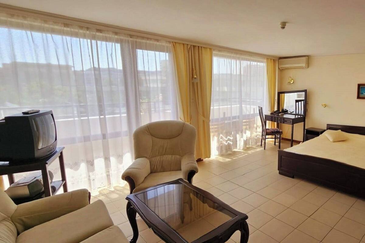 Une chambre d’hôtel équipée d’un lit, d’une chaise, d’un bureau, d’une télévision et offrant une vue sur l’extérieur.
