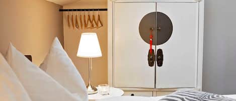 A hotel room with a bed, a nightstand with a lamp, a wardrobe, and a window.