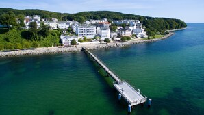 A coastal town with a pier extending into the water, surrounded by residential buildings and greenery. - Herring Gull, Germany (Sassnitz)