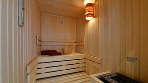 A wooden sauna with benches, a wooden bucket, and a wall-mounted heater. - Herring Gull, Germany (Sassnitz)
