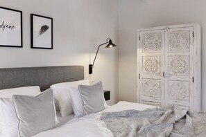 A bedroom with a bed, pillows, a lamp, and a wardrobe with decorative panels.