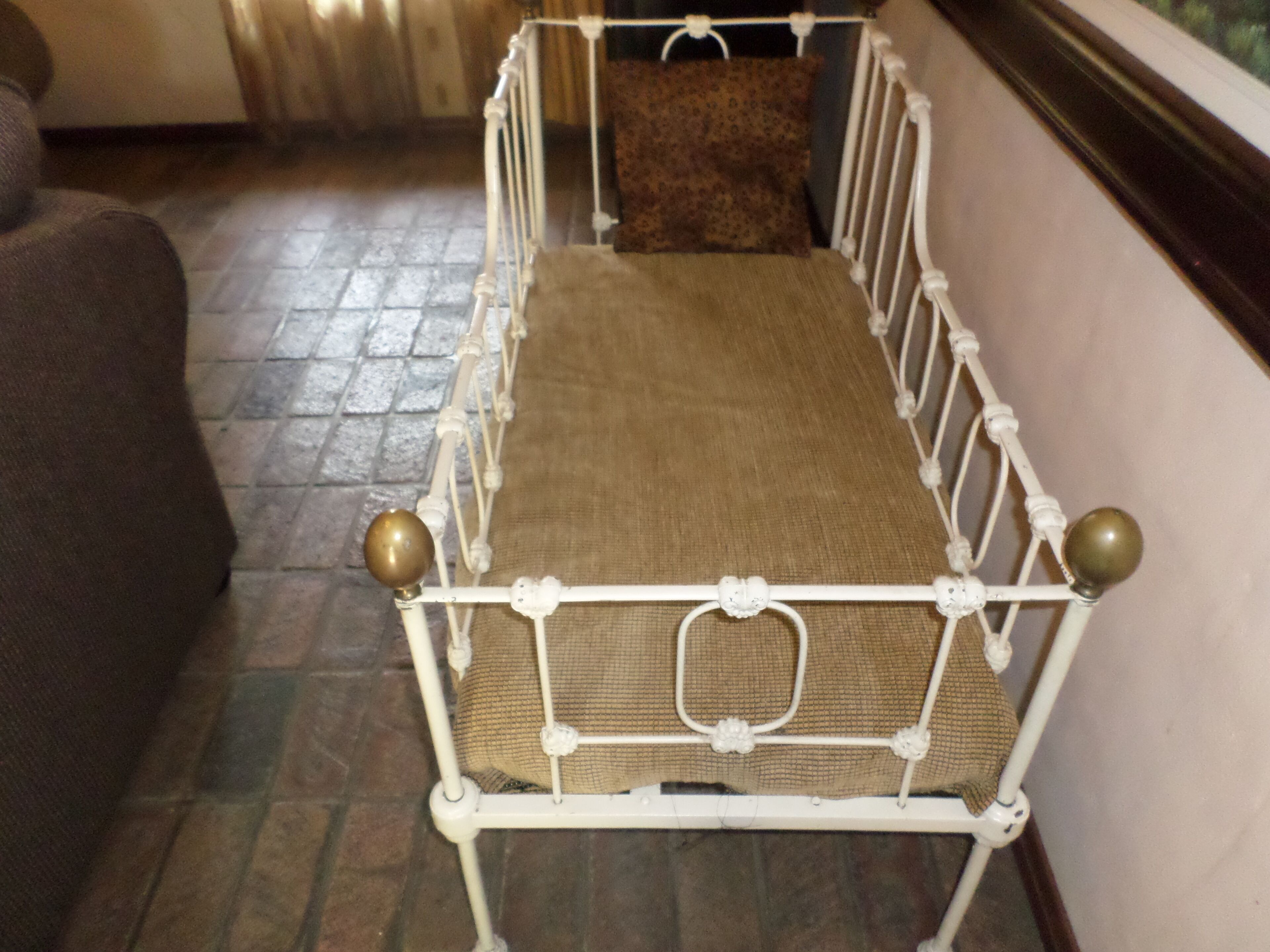 Estructura de cama metálica con un colchón, una almohada y suelo de madera.