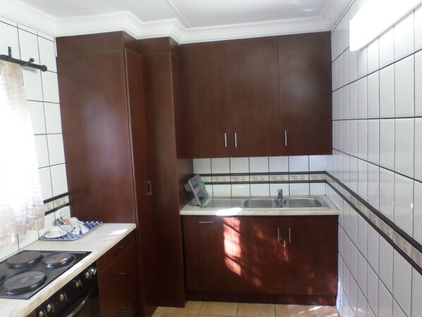A kitchen with dark wooden cabinets, a white countertop, and a tiled backsplash.