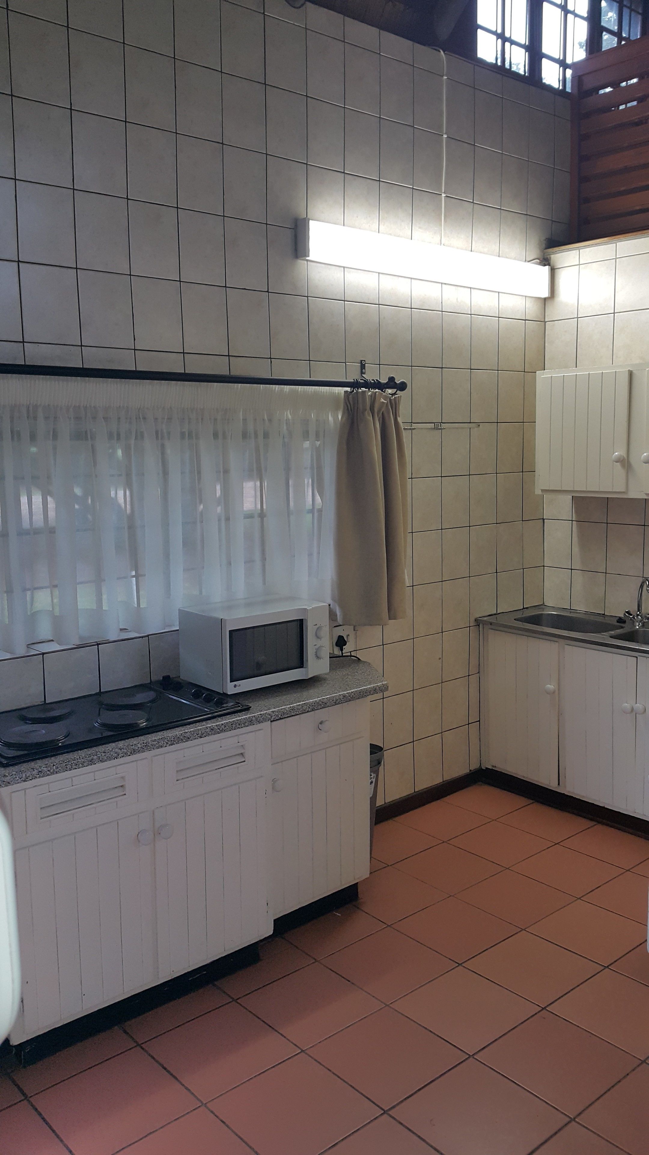 A kitchen with white cabinets, a microwave, a stove, and a sink.