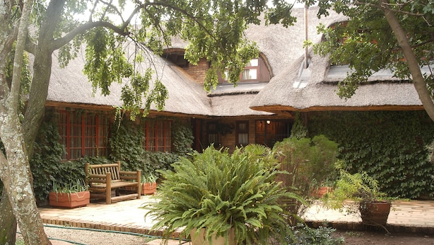 Une maison traditionnelle avec un toit de chaume, un banc en bois et des plantes en pot.