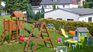 Une aire de jeux dotée de diverses installations, notamment un portique en bois, des toboggans et des structures d’escalade.