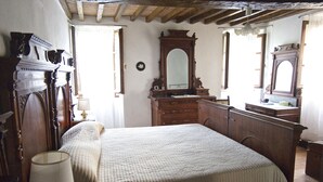 Un dormitorio con una cama grande, un aparador de madera y dos espejos adosados a la pared.