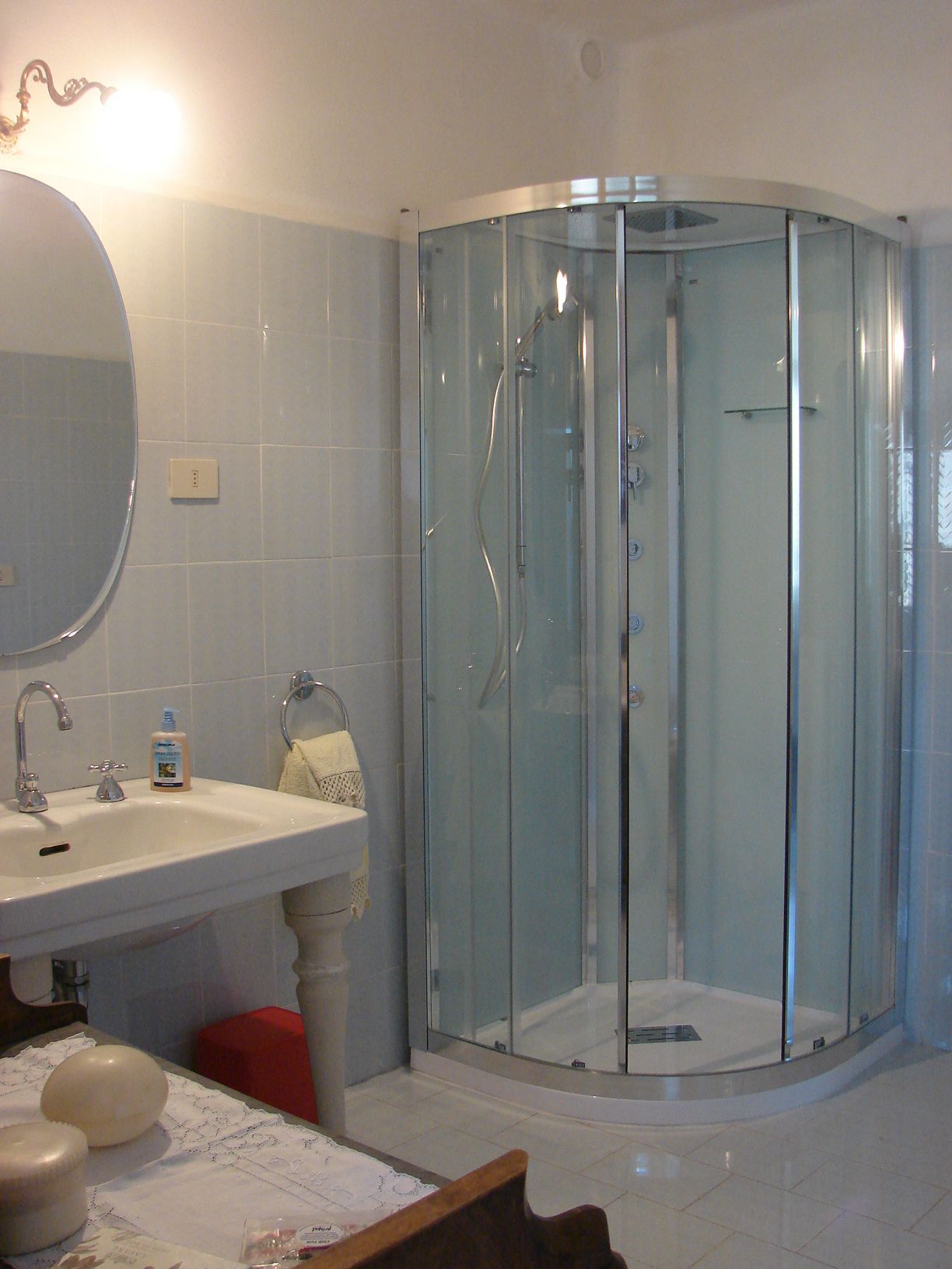 Une salle de bain avec une douche à parois de verre, un lavabo avec un miroir et des articles de toilette posés sur le comptoir.