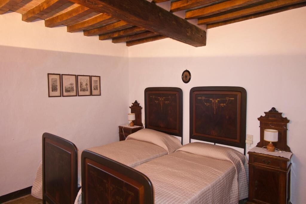 A bedroom with a wooden bed, a nightstand with a lamp, and framed pictures on the wall.