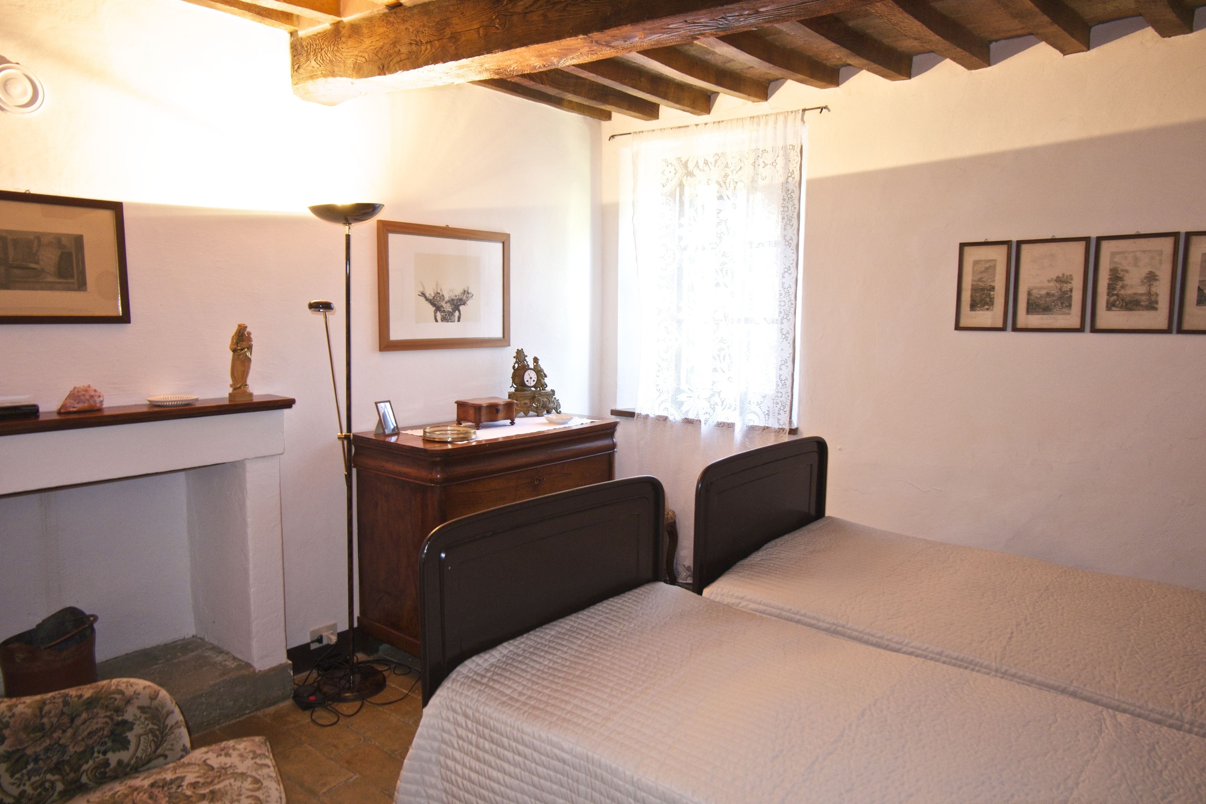 Un dormitorio con una cama, un escritorio, una lámpara y cuadros en la pared.