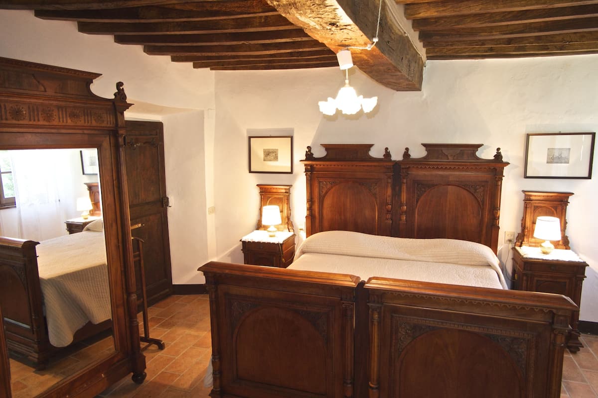 A traditional wooden four-poster bed with matching nightstands, a large mirror, and a chandelier.