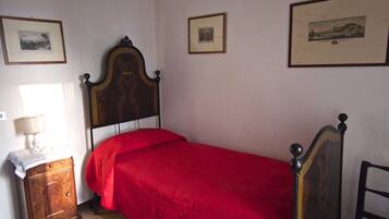 Un dormitorio con una cama de madera, una mesita de noche con una lámpara y tres cuadros enmarcados en la pared.