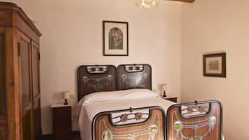 Une chambre à coucher avec un lit double, une tête de lit en bois, un lustre, une armoire et des tableaux encadrés accrochés au mur.