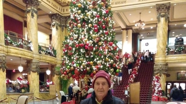 A grand lobby with a large Christmas tree, marble columns, and a red carpeted floor.