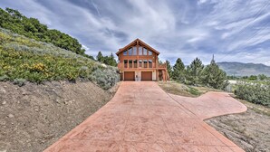 A modern house with a large driveway leading to a garage, surrounded by lush greenery and hills. - Spacious Hilltop Cabin w/ Deck & Scenic Views! (Eden)