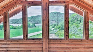 A wooden cabin with a triangular roof and large windows offering a view of a green landscape and hills. - Spacious Hilltop Cabin w/ Deck & Scenic Views! (Eden)