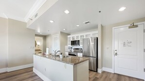 A modern kitchen with white cabinetry, stainless steel appliances, and a granite countertop.