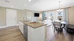A modern kitchen with a central island, white cabinetry, and a dining area with a table and chairs.