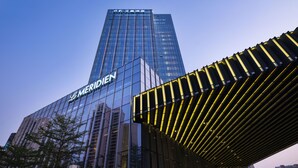 Un hotel de gran altura con fachada moderna de vidrio y el nombre "MERIDIEN" visible en grande.