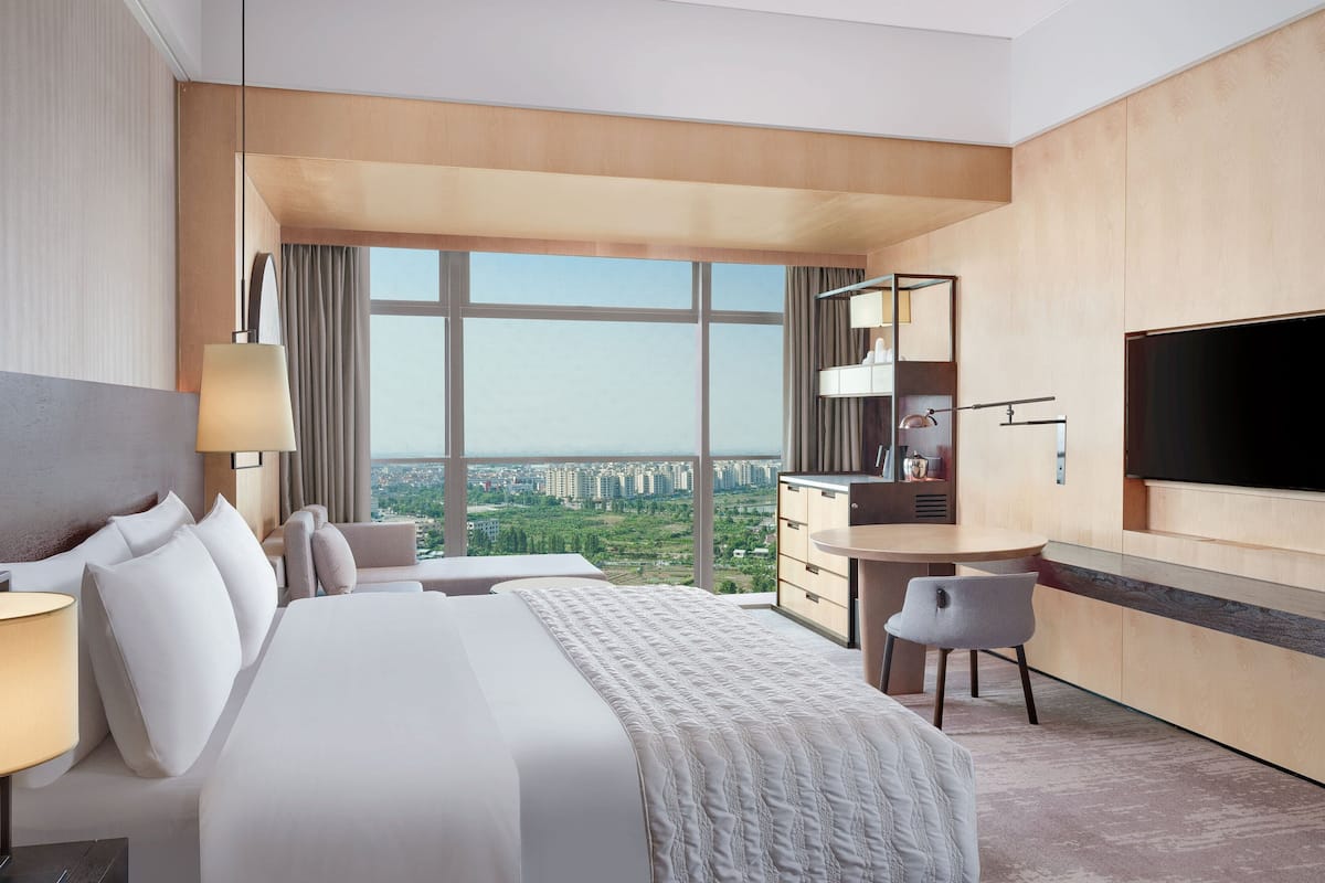 Una habitación de hotel moderna con una cama grande, un escritorio, una silla y un televisor.