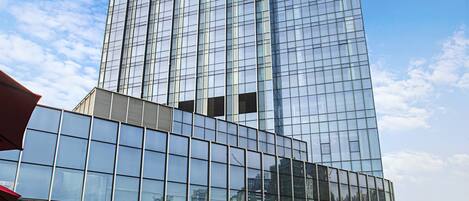 Ein modernes Gebäude mit Glasfassade und einer Grünfläche mit Sitzgelegenheiten.