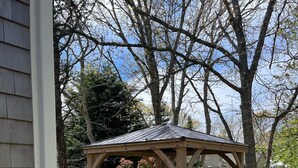 Ein hölzerner Pavillon mit Tisch und Stühlen in einem Garten.