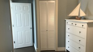 Ein Korridor mit einer weißen Tür, einem beige-farbenen Klappschrank und einer weißen Kommode mit Schubladen.