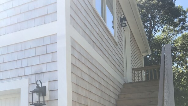 Eine Treppe führt zu einem Haus mit einer weißen Tür und einer Laterne an der Wand.