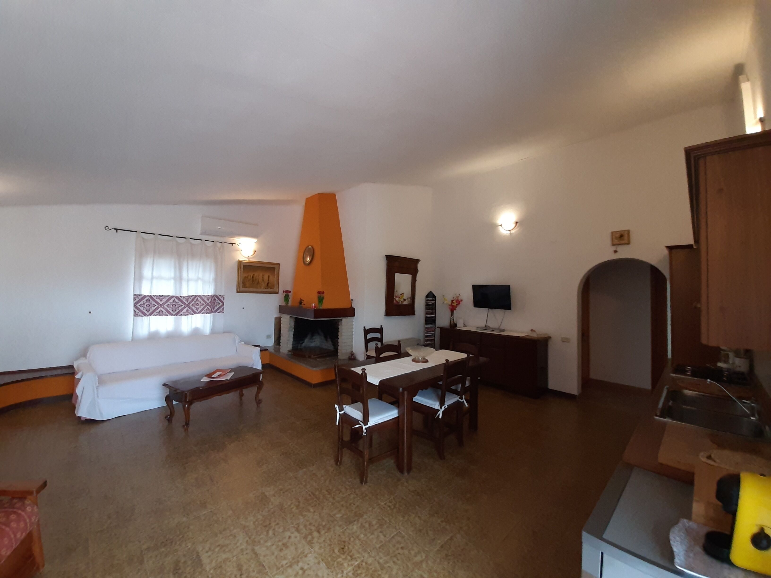 Una sala de estar con chimenea, un sofá, una mesa de comedor con sillas y un televisor.