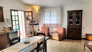 A cozy living room with a dining table, two chairs, a sofa, a cabinet, and a ladder.