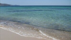 Une plage à l’eau turquoise et limpide, bordée d’un rivage sablonneux.