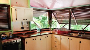 A kitchen with a gas stove, cabinets, a sink, and a window with blinds. - Top of the Hill Two Bedroom Apartment, Rodney Bay (Gros Islet)