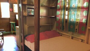 A bunk bed with a red pillow and a white mattress, a small stool, and a colorful striped rug. - Top of the Hill Two Bedroom Apartment, Rodney Bay (Gros Islet)