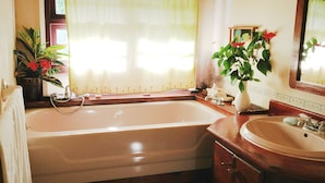 A bathroom with a bathtub, a sink, a mirror, and two potted plants. - Top of the Hill Two Bedroom Apartment, Rodney Bay (Gros Islet)
