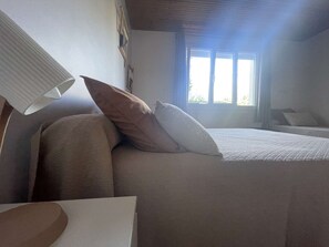 Une chambre à coucher avec un lit, des oreillers, une lampe et une fenêtre.