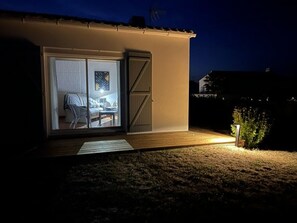 A house with a sliding glass door leading to a bedroom with a bed and a chair.