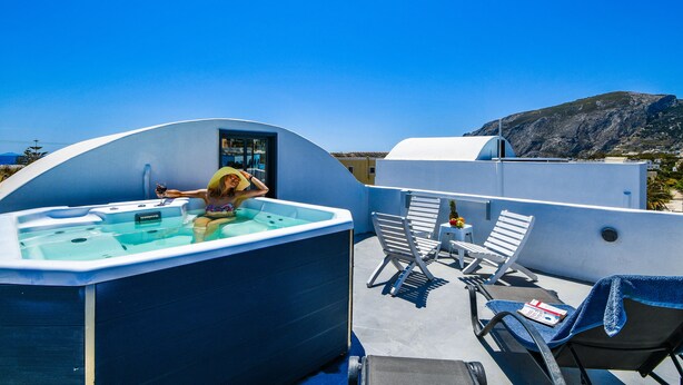 Una terraza en la azotea con un jacuzzi, sillones de descanso y vistas a las montañas.