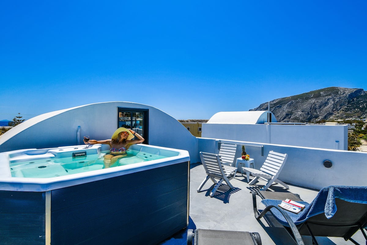 Una terraza en la azotea con un jacuzzi, sillones de descanso y vistas a las montañas.