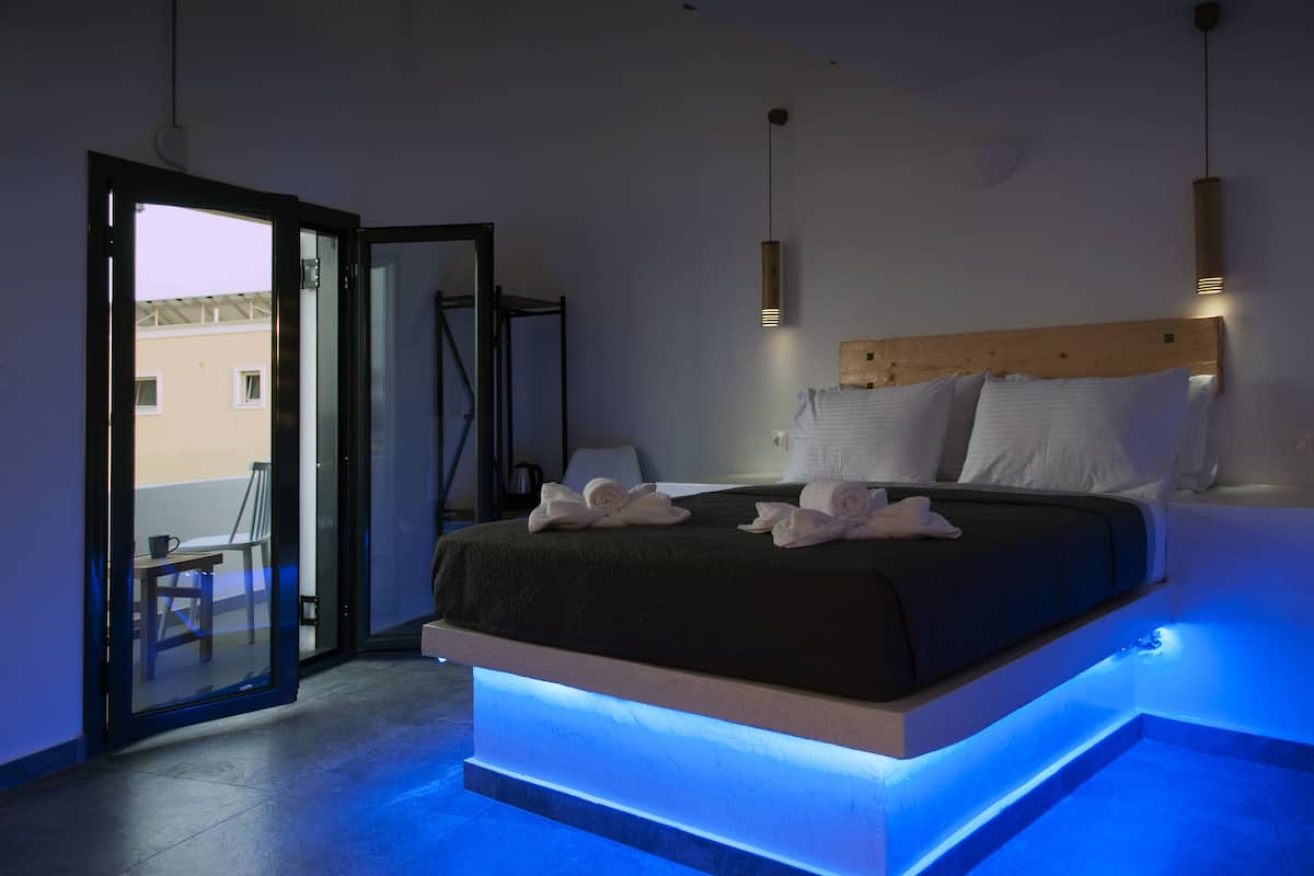 Un dormitorio moderno con cama, lámparas de noche y una puerta de cristal que da a un espacio exterior.